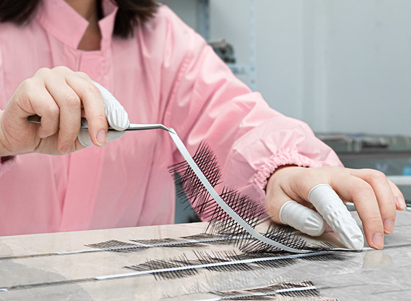 Cleanroom lash artisan carefully arranging precision lash strips with tweezers